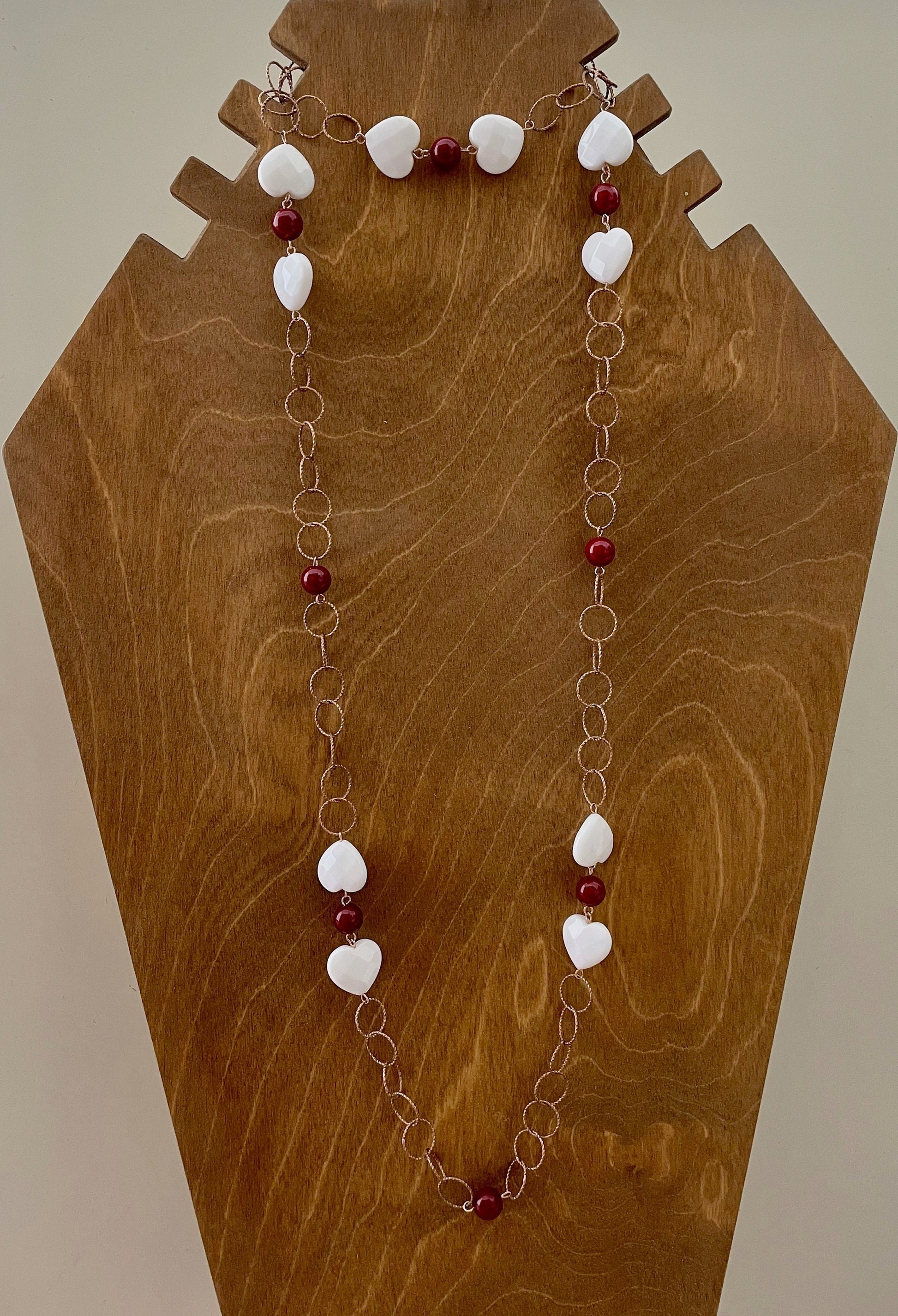 Collana lunga a maglia larga con cuori bianchi e perle rosse.&