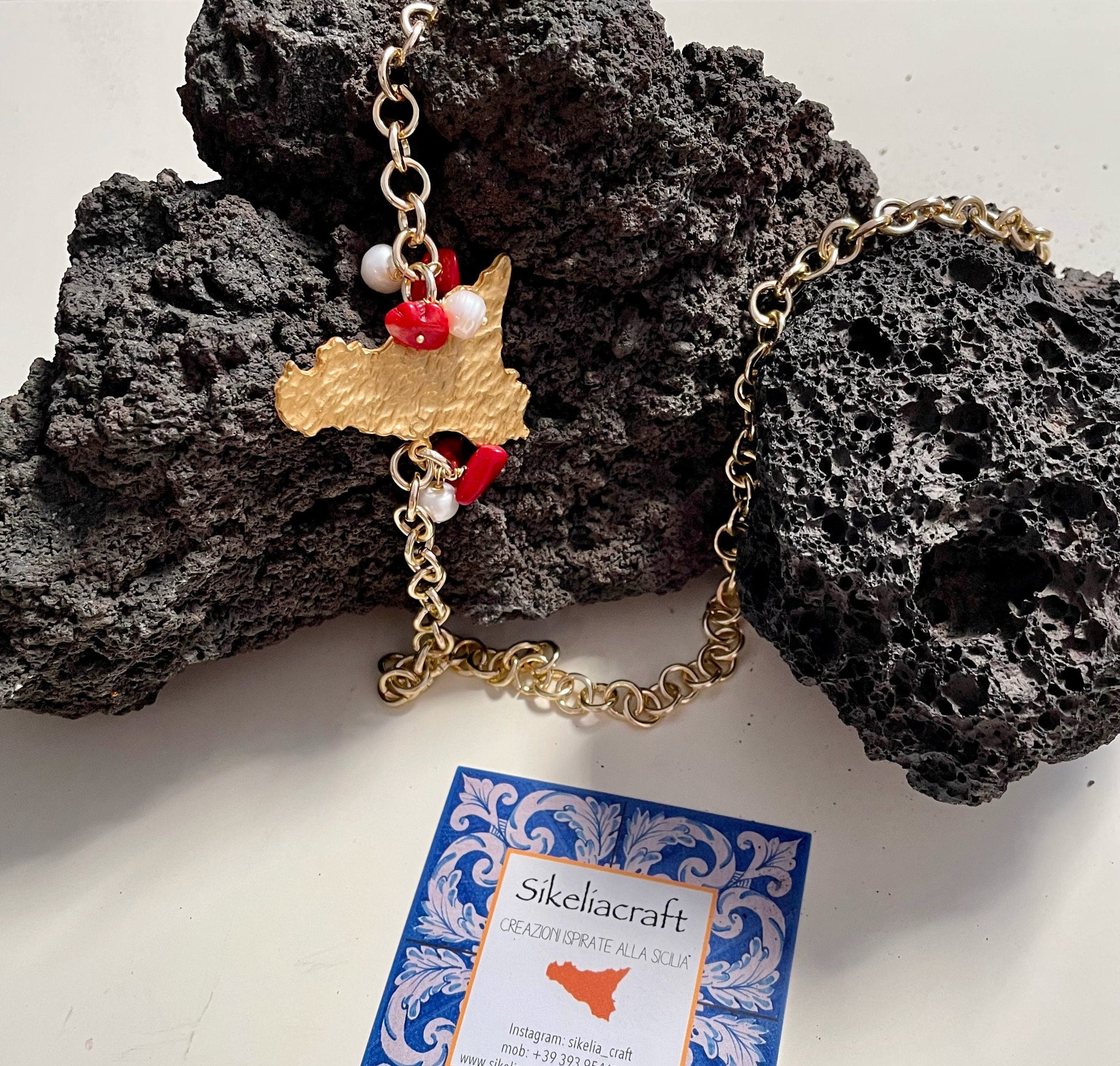 Collana con ciondolo sicilia in ottone, catena alluminio, perle di fiume e chips di corallo.ç