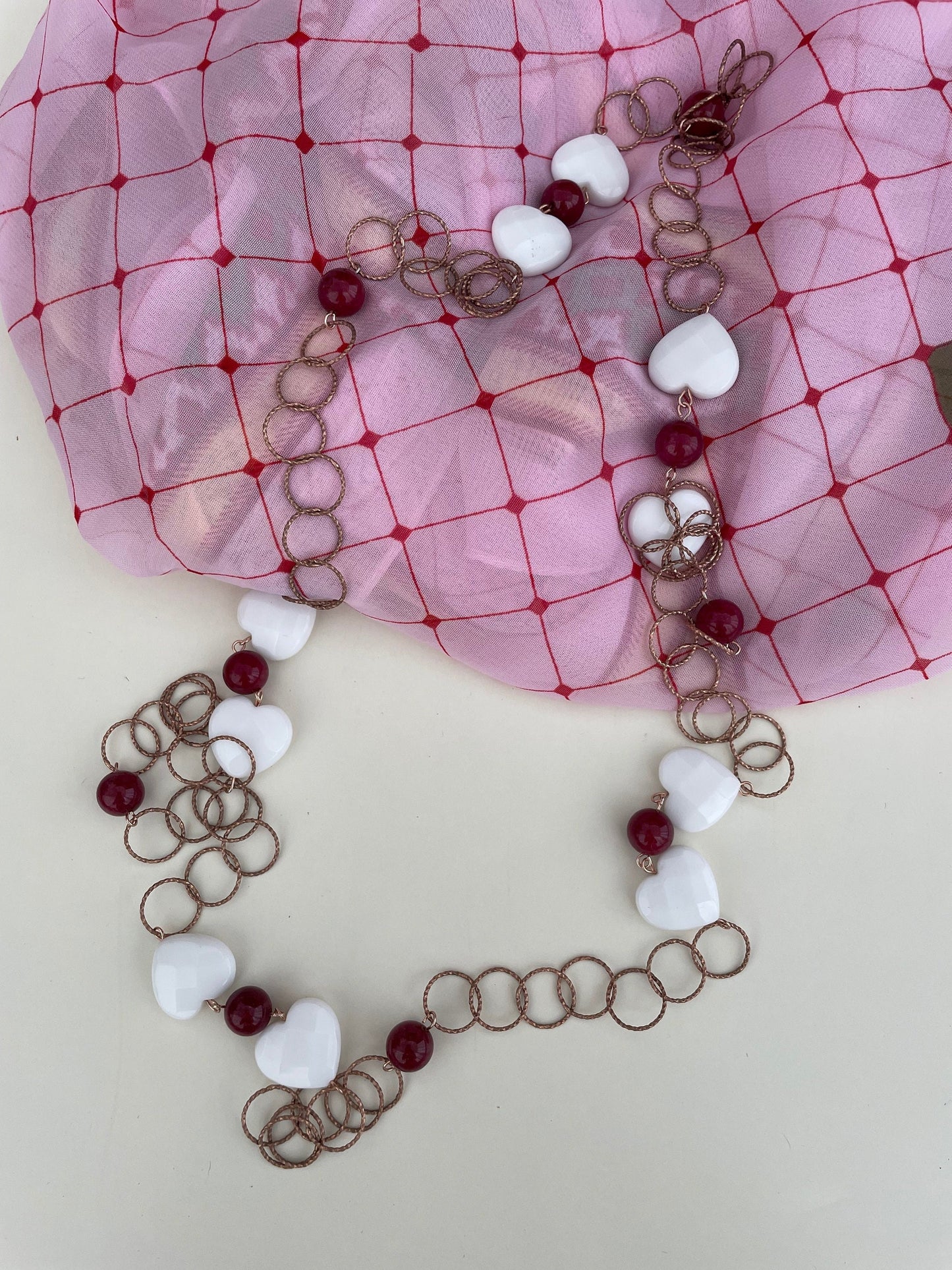 Collana lunga a maglia larga con cuori bianchi e perle rosse.&