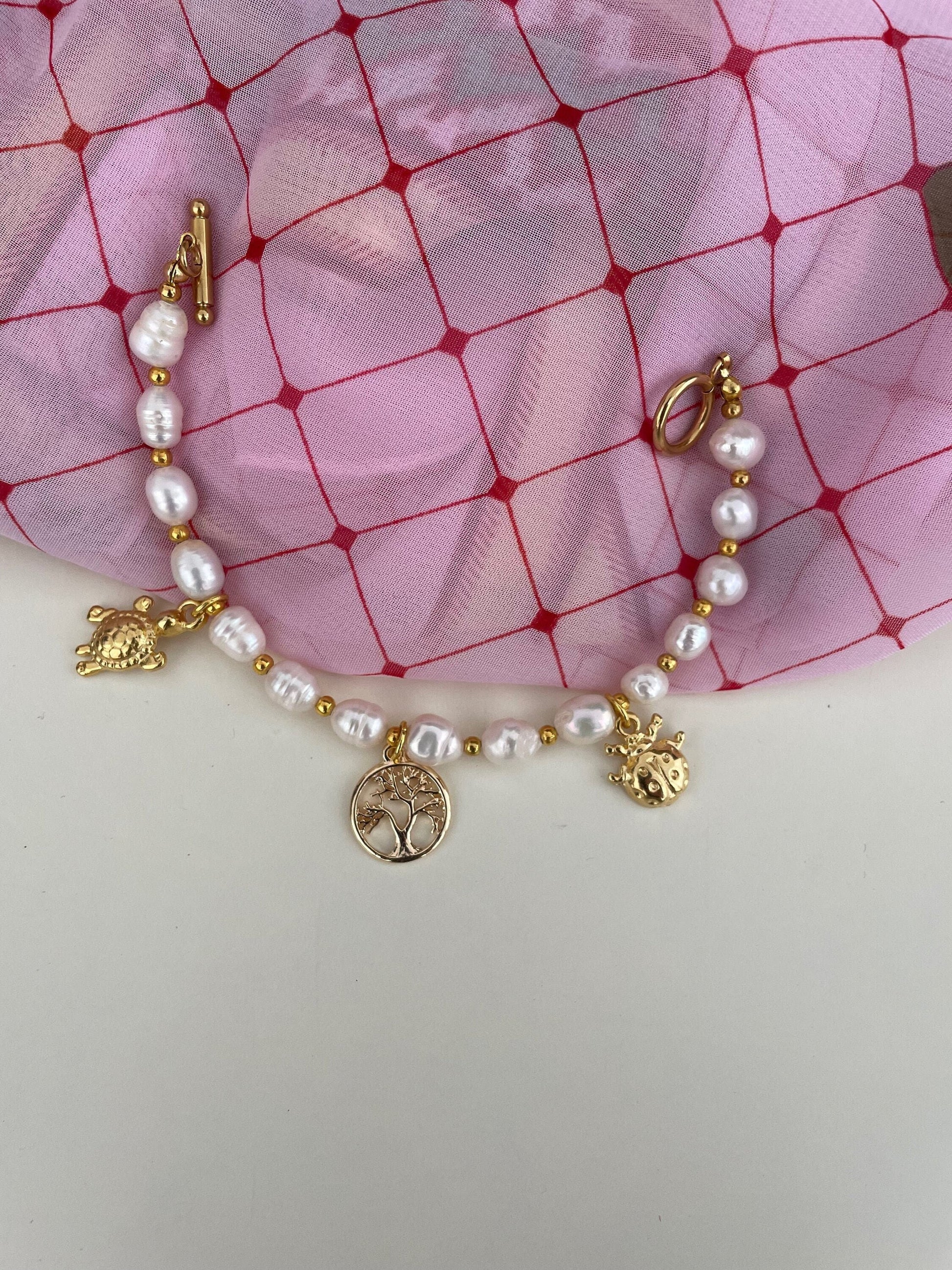 Bracciale con filo di perle di fiume e perline dorate e charms assortiti)