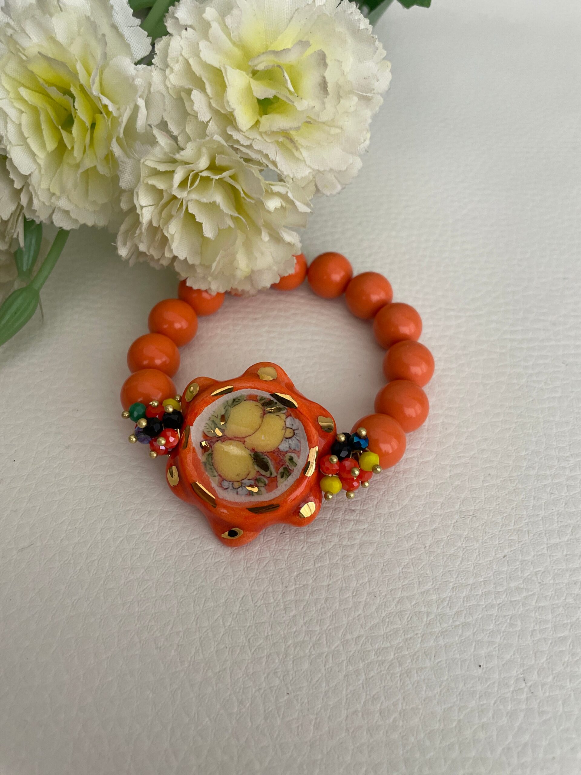 Bracciale Sikelia, bracciale siciliano, tamburello di ceramica Caltagirone, bracciale elastico con perle di pasta di corallo color salmone. Bracciali caratteristici siciliani